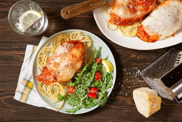 Slow-Cooker Chicken Parmesan on a plate swerved over pasta with a side of salad