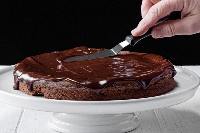 Decorating the baked Flourless Chocolate Cake on cake stand