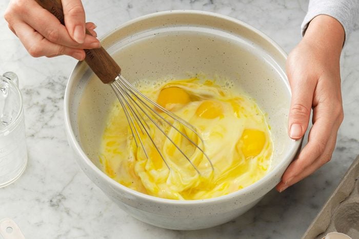 A person whisking milk eggs in a large bowl