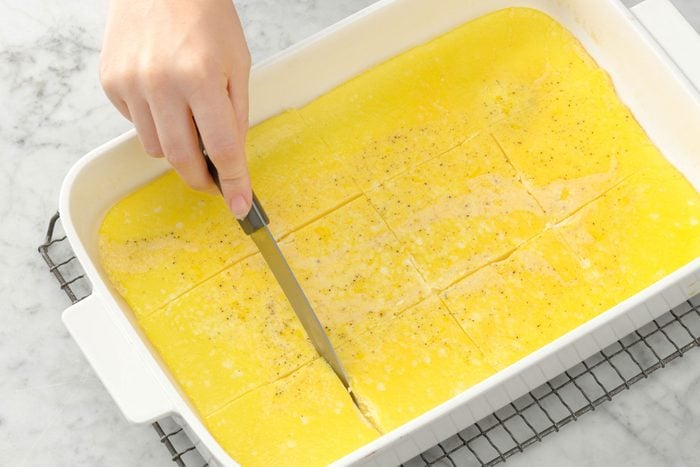 A person cutting baked eggs in a baking tray