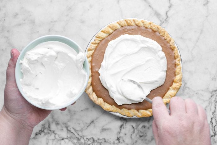 smoothing the whipped cream on french silk pie, marble background