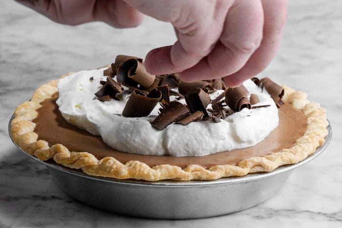 Garnishing French Silk Pie with chocolate curls, marble background