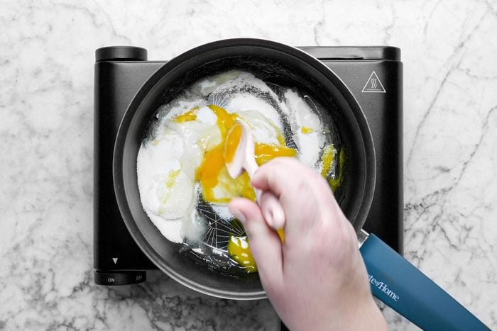 mixing sugar and eggs in a saucepan , marble background