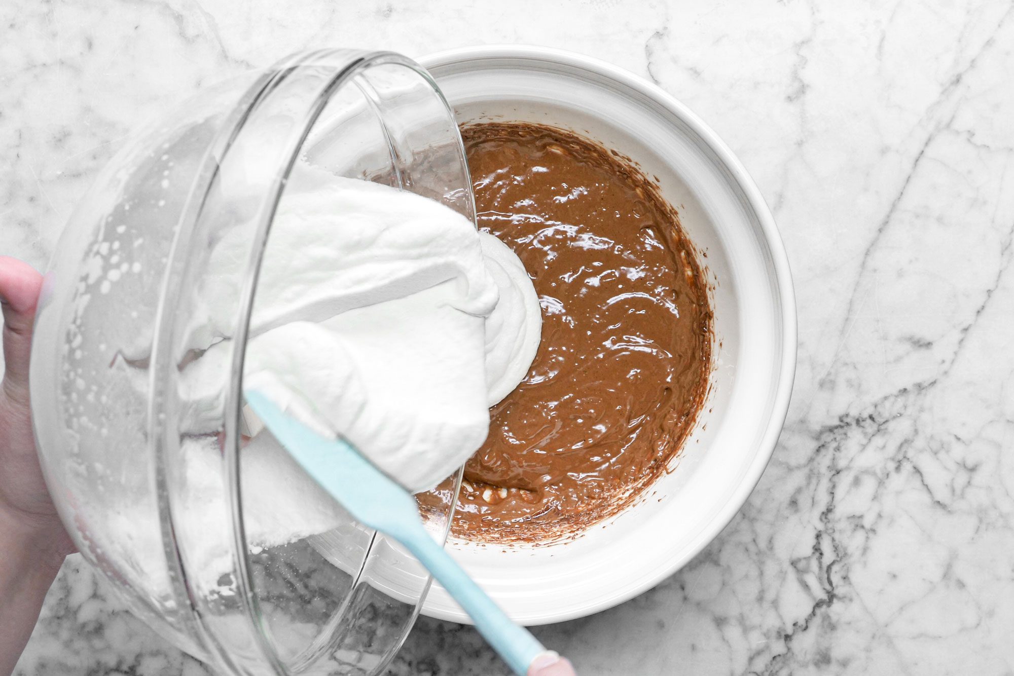 pouring whipped cream into a bowl of chocolate mixture, marble background