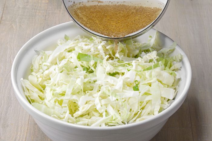 Mixing vinegar dressing in shredded into cabbage 