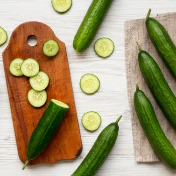 cucumbers and sliced cucumbers on a wooden cutting board