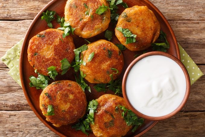 Tasty Aloo Tikki is a popular Indian street food which is basically crispy and spicy potato patty with yogurt close-up on the table. Horizontal top view