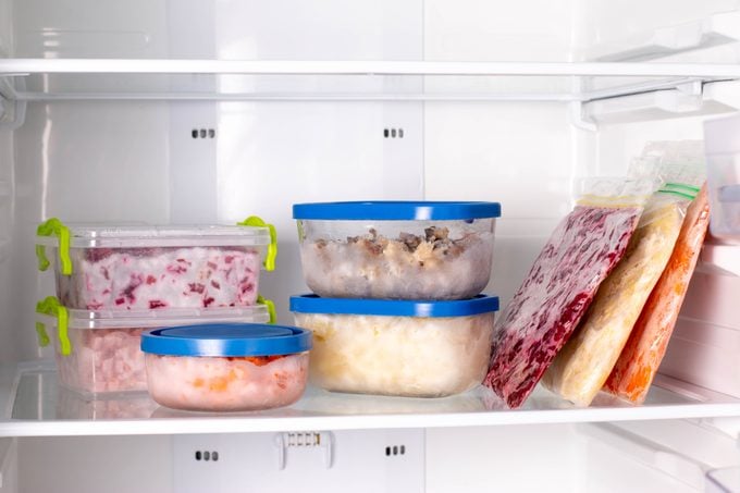 Plastic bags and containers with different frozen vegetables in refrigerator. Food storage