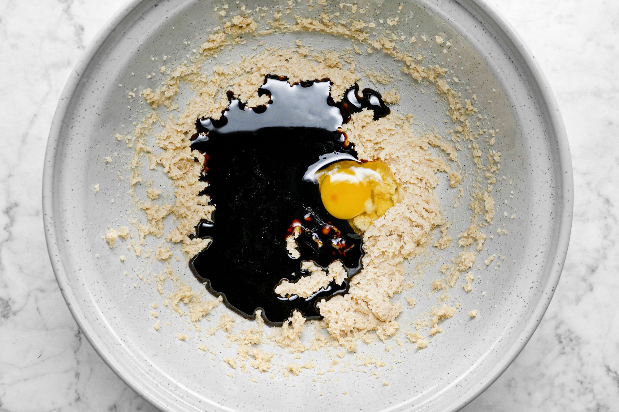 Egg Yolk, Molasses and Butter Mixed Brown Sugar in A Large Mixing Bowl on Marble Surface