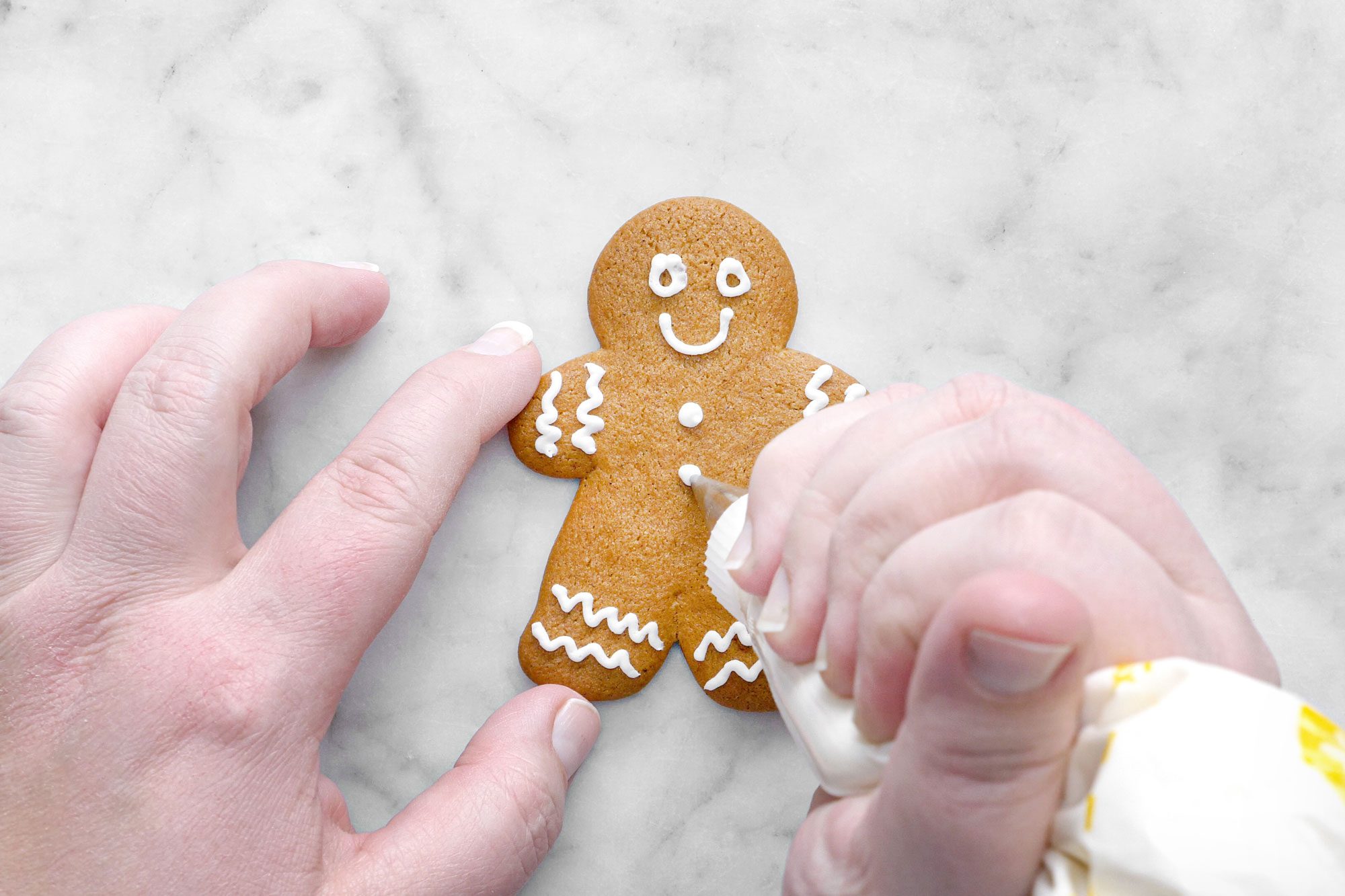 Decorating Gingerbread Cutout Cookies on Marble Surface