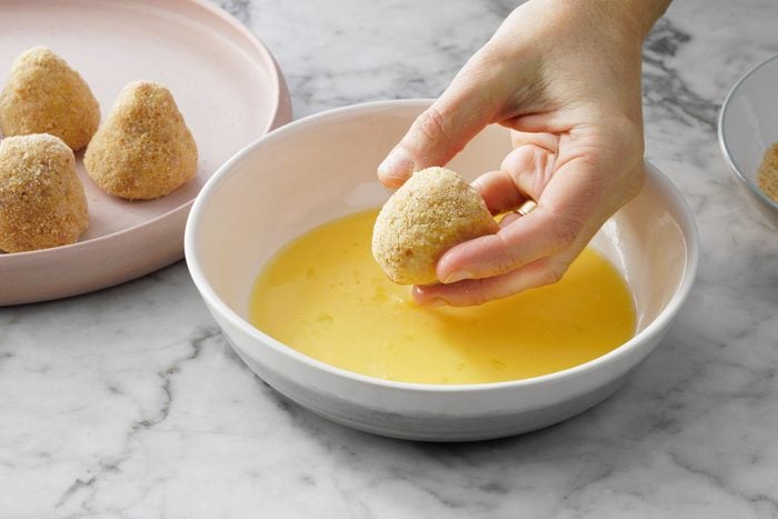 Dipping the bread crumb covered ham balls in egg water mixture