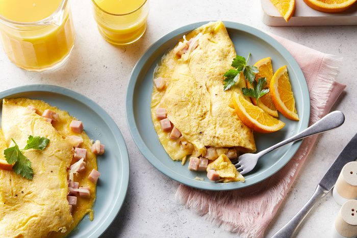 Ham And Cheese Omelet served on plate with orange slices and juice glasses on side