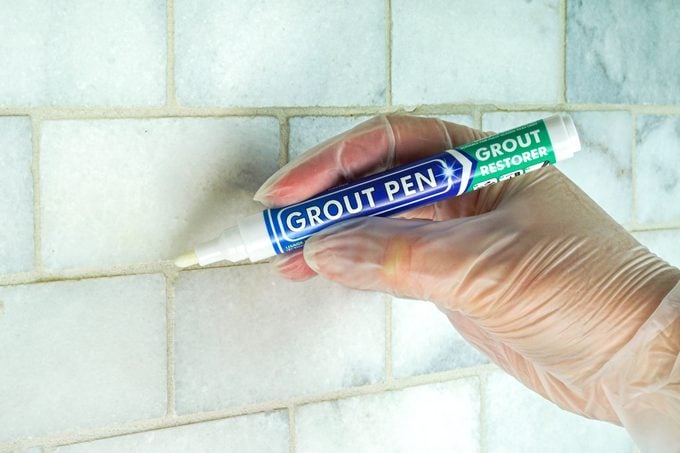A person using Grout Pen on a wall