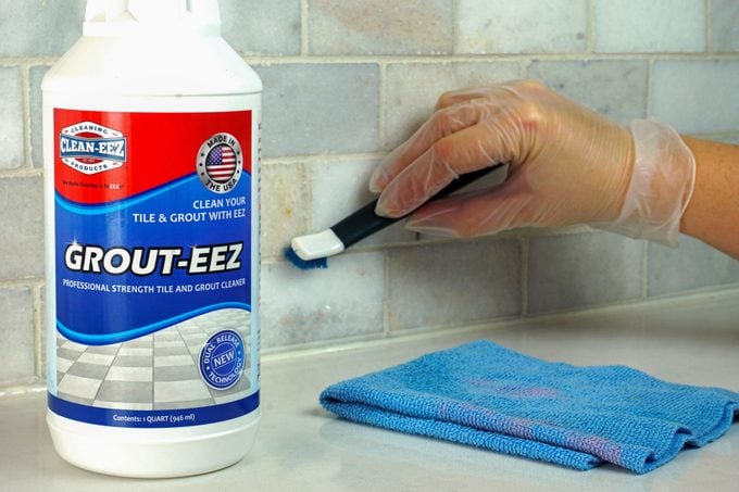 A person cleaning wall with a tooth brush with a product place on side
