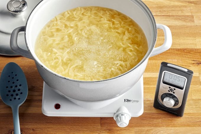 pasta in boiling water next to a timer set to a time that would leave the pasta at an al dente level of doneness