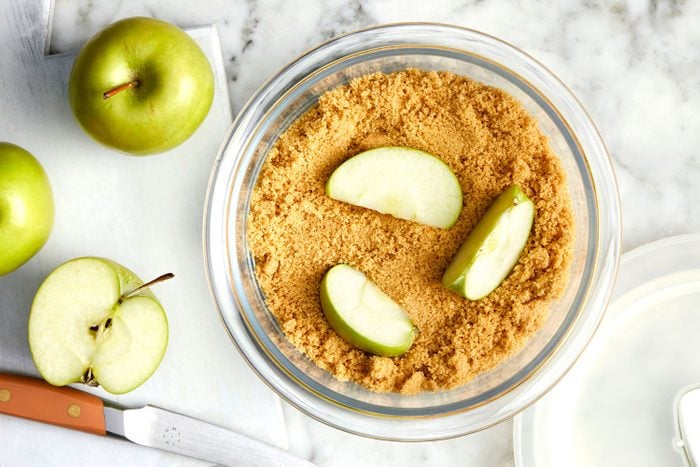 Adding apple wedges to a container of brown sugar