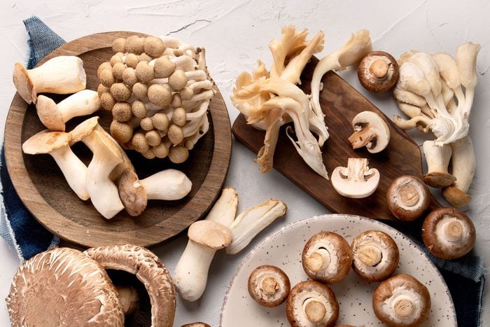 Variety of raw mushrooms on light gray background. Vegan food cocnept. Top view, flat lay