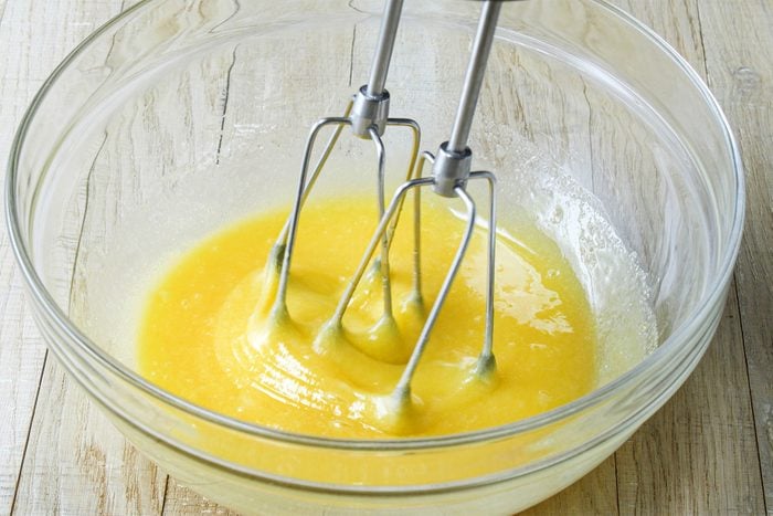 A bowl of yellow liquid with whisk