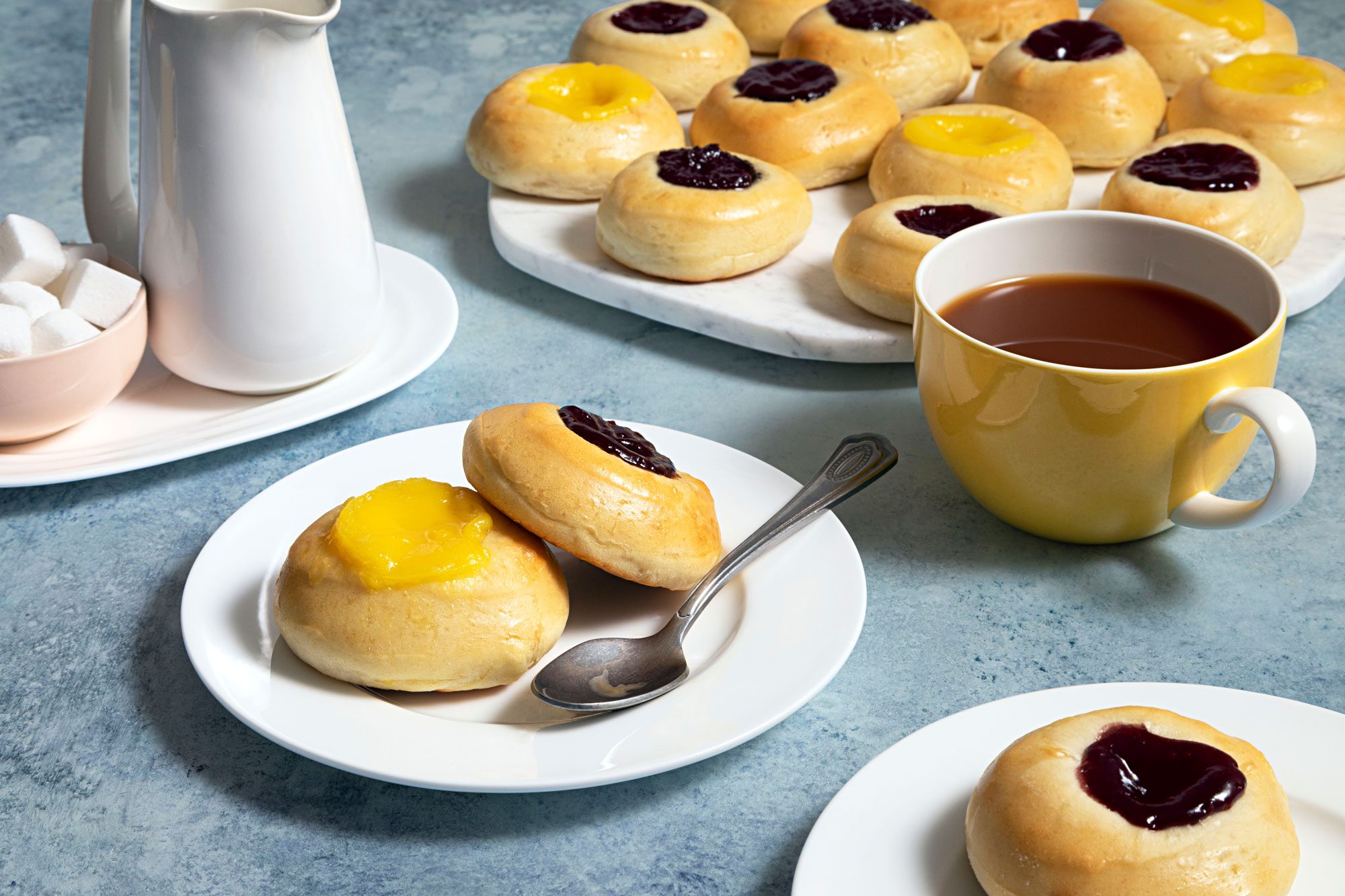 Kolaches served on a small plate with a spoon and a cup of hot chocolate placed next to it