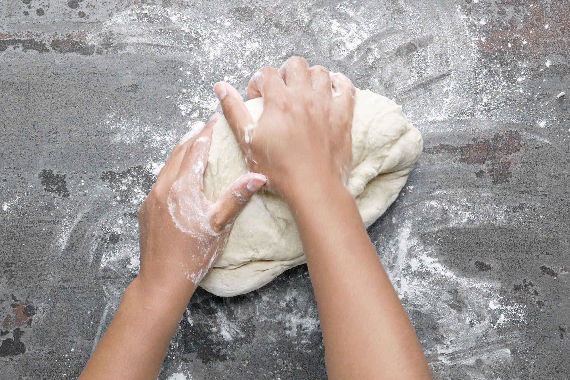 a person kneading dough on a floured surface