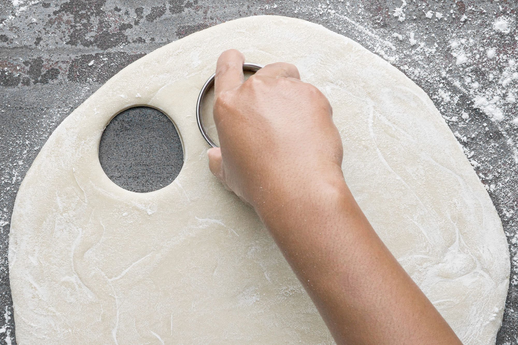 cutting the dough into a round shape with a dough cutter