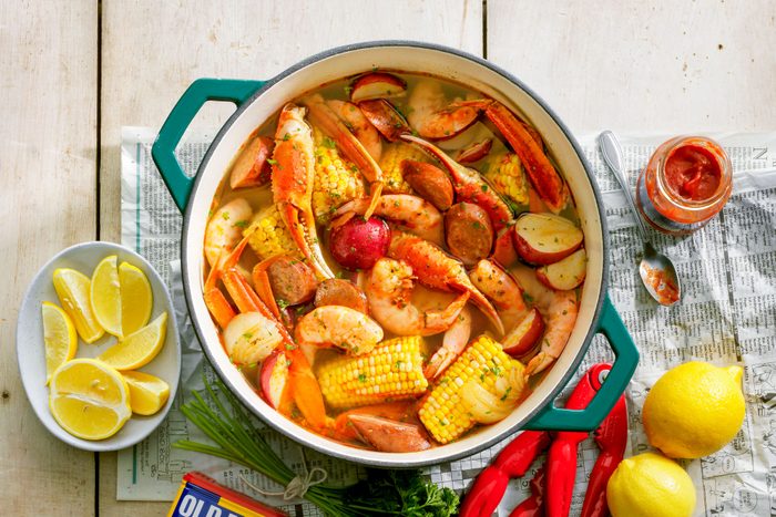 Lowcountry Boil in A Ceramic Cooking Pot on Wooden Surface with Lemon Wedges