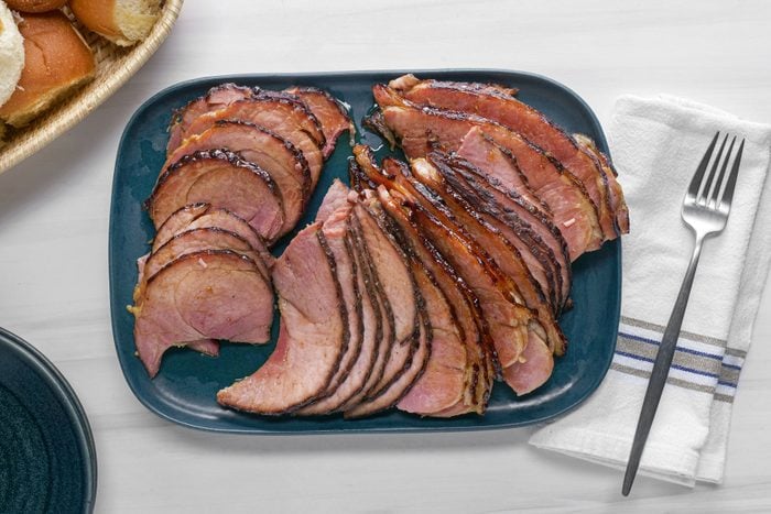 Maple Glazed Ham served in a plate with a fork on a side on a table cloth