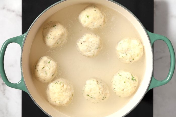 Matzo balls boiling in a green pan