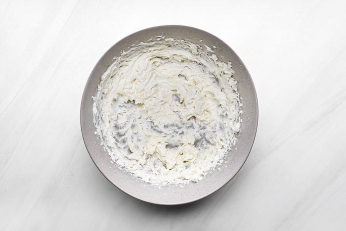 beaten cream cheese in a large bowl on marble surface
