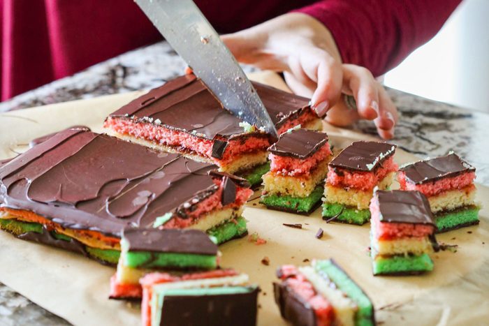 A Person Cutting Passover Rainbow Cookies into Pieces with A Knife