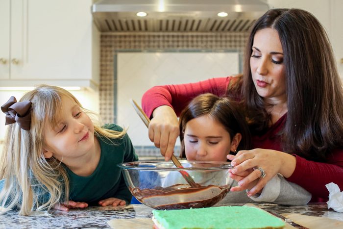Trio of Daughters and Mother Mixing Chocolate Glaze in a Large Glass Bowl