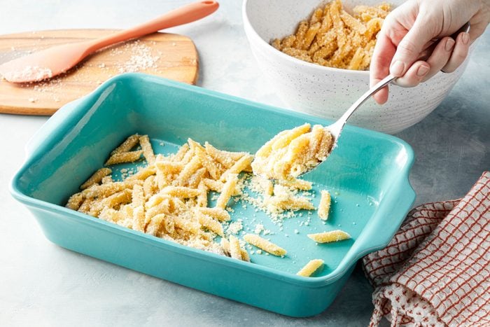 Adding parmesan cheese and paste in grated baking dish