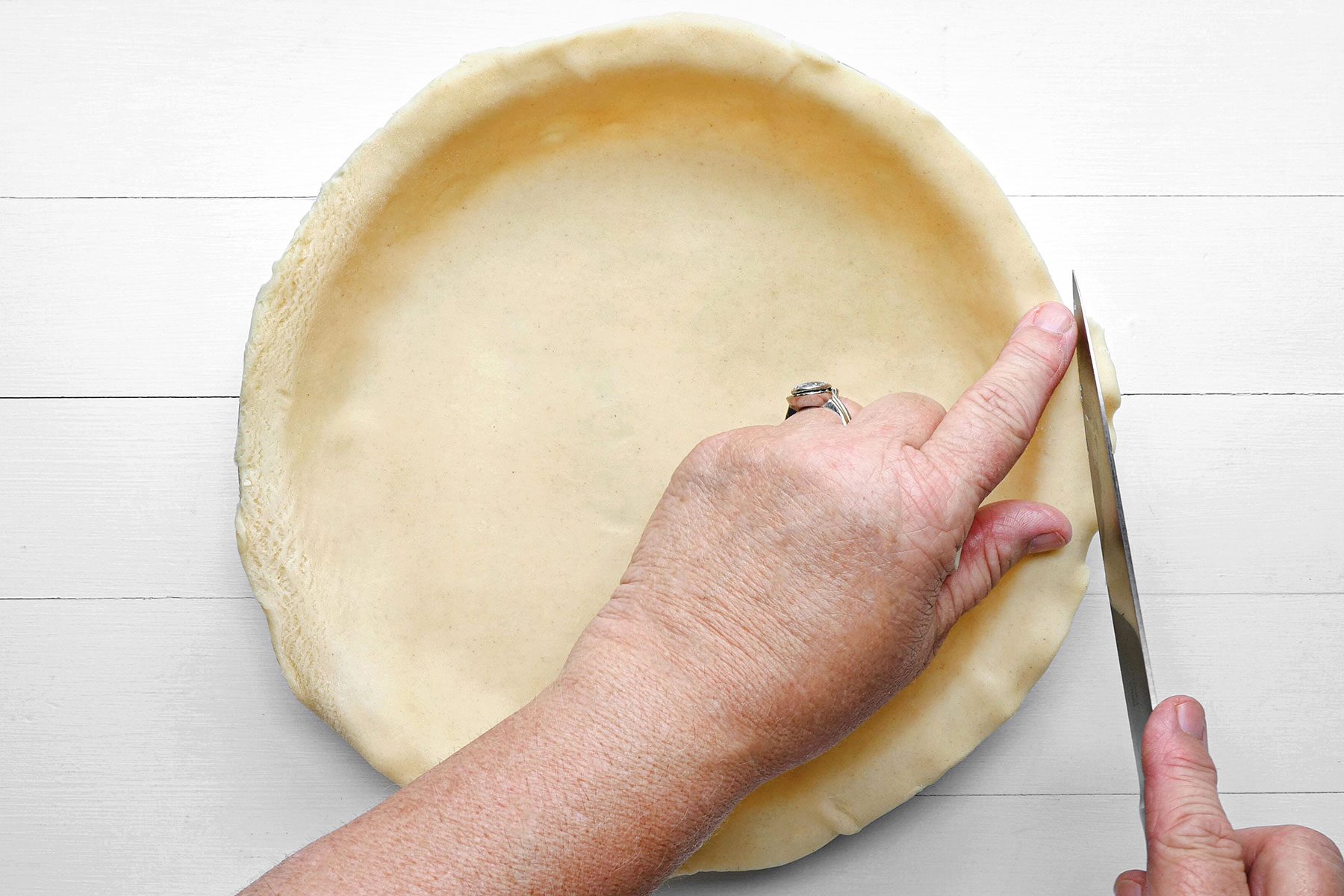 Trimming the bottom pie dough on baking tray