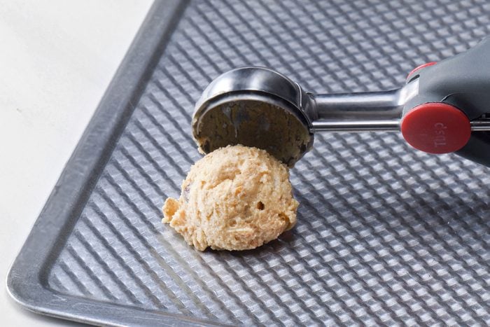 Dropping cookie dough with a scooper on baking tray