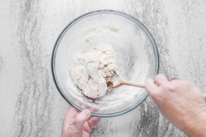 Preparing the dough in a large bowl using a wooden spatula
