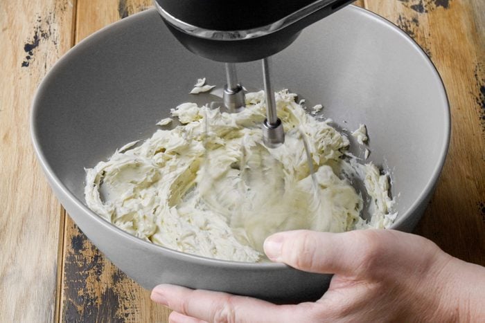 Beating the cream cheese with a hand mixer in a large bowl