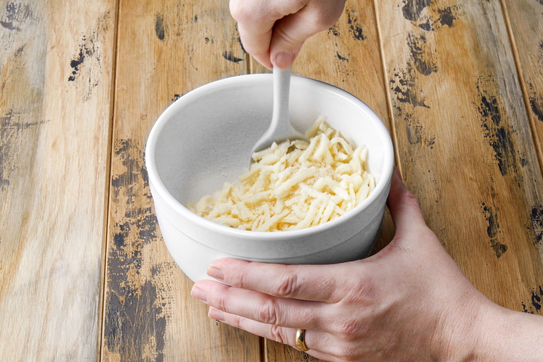 Combining the mozzarella and Parmesan in a small bowl with a spoon