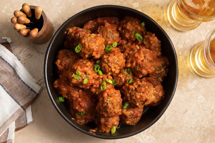 A bowl of Porcupine Meatballs with savory sauce and beer