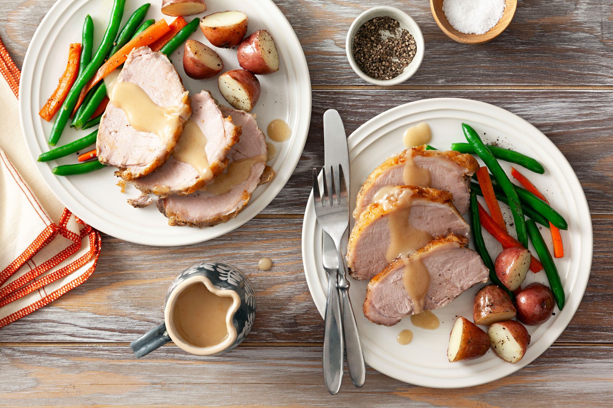 A tempting plate of pork roast, veggies, and gravy on a wooden table