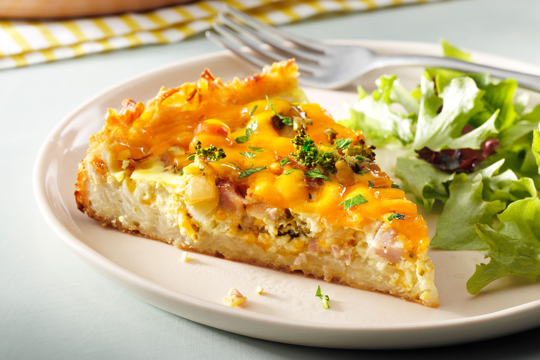 Slice of Potato Crust Quiche served on plate with lettuce