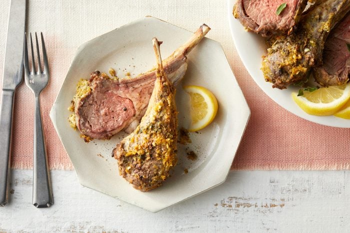 A plate of rack of lamb with lemon on a table