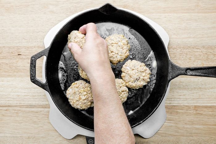 a person frying Salmon Patties in a cast iron skillet
