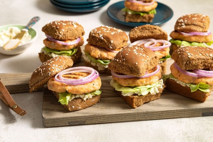 Salmon Sliders served on a wooden plate with onion and lettuce