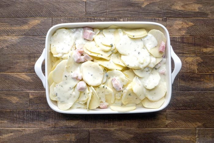 Scalloped Potatoes And Ham in a rectangular baking dish on a wooden surface