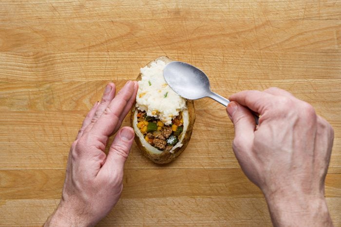 Layering the potato filling on potato shell with a spoon