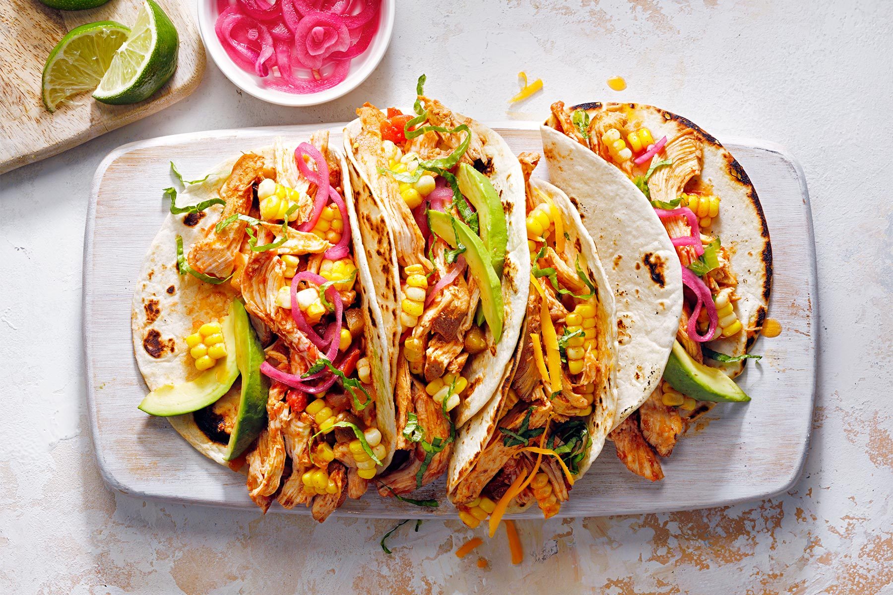 Slow Cooker Chicken Tacos served on plate; bowl of onion and lemon wedges
