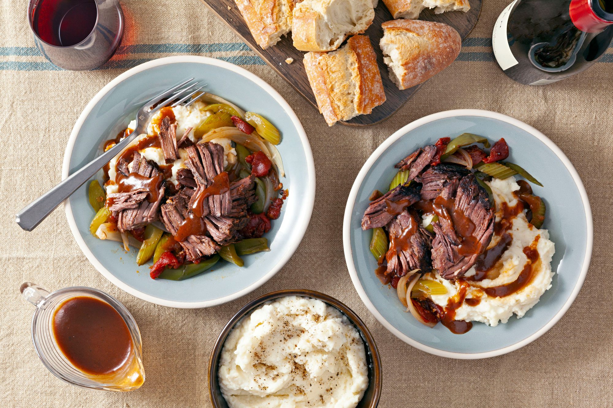 Delicious Slow Cooker Chuck Roast meal with wine and bread on two plates