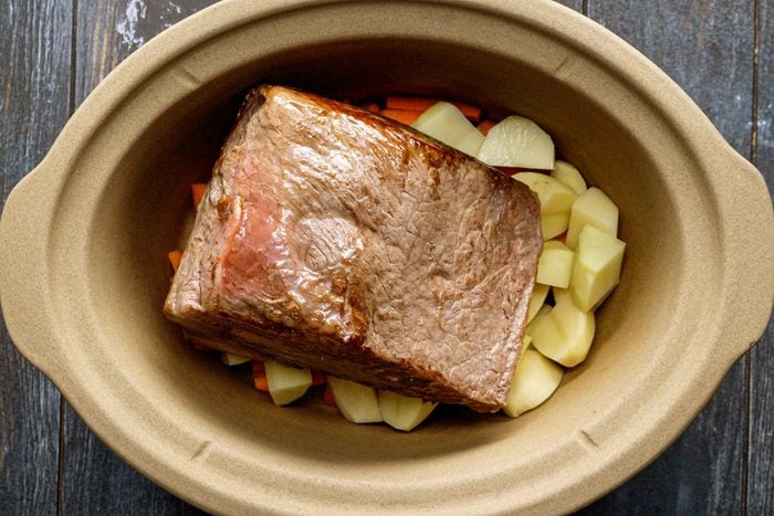 Rump Roast, Carrots and Potatoes in a Slow Cooker on a Wooden Surface