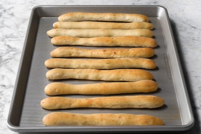 Soft Garlic Breadsticks on a baking tray on marble surface