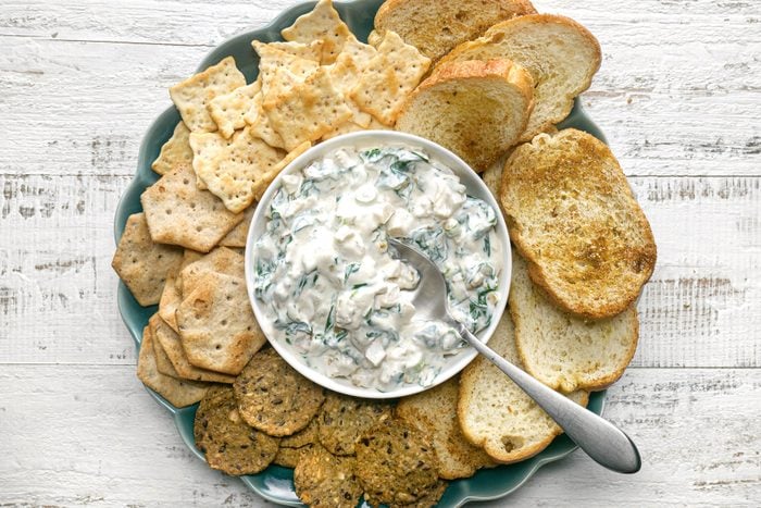 A plate of crackers with a bowl of spinach dip
